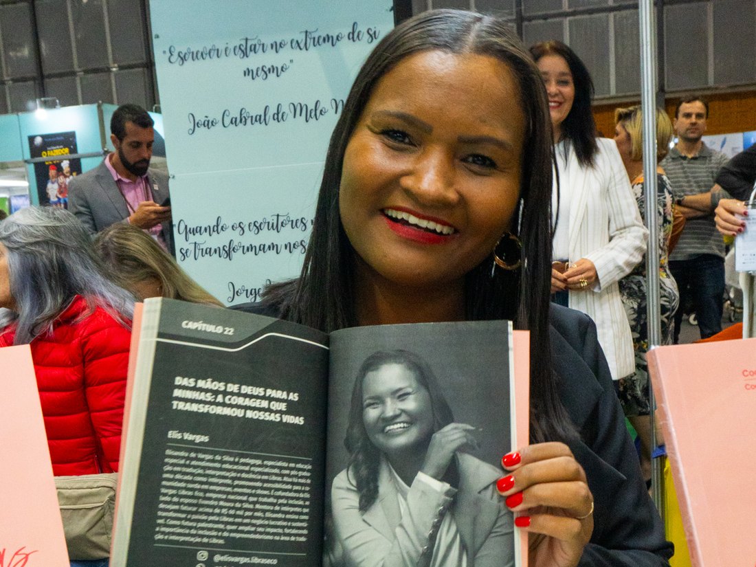 Elisandra Vargas segurando o livro aberto no capítulo que escreveu